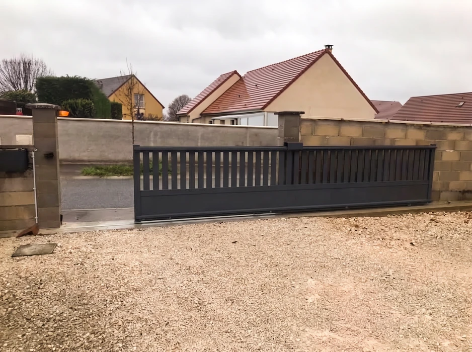 Portail coulissant motorisé en aluminium laqué anthracite (RAL 7016), monté sur rail au sol, avec lames verticales espacées