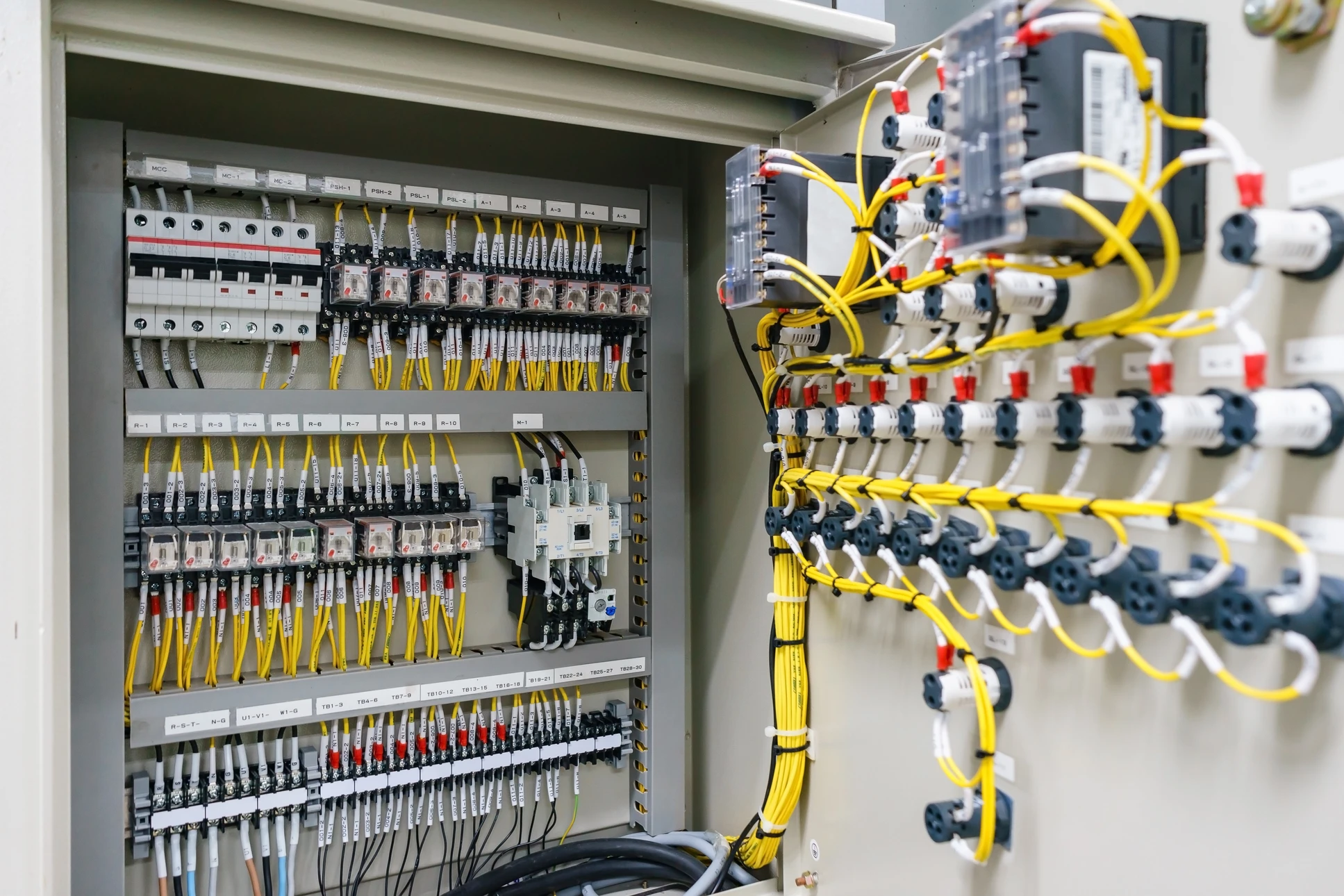 Intérieur d'armoire électrique industrielle ouverte révélant l'installation électrique complexe