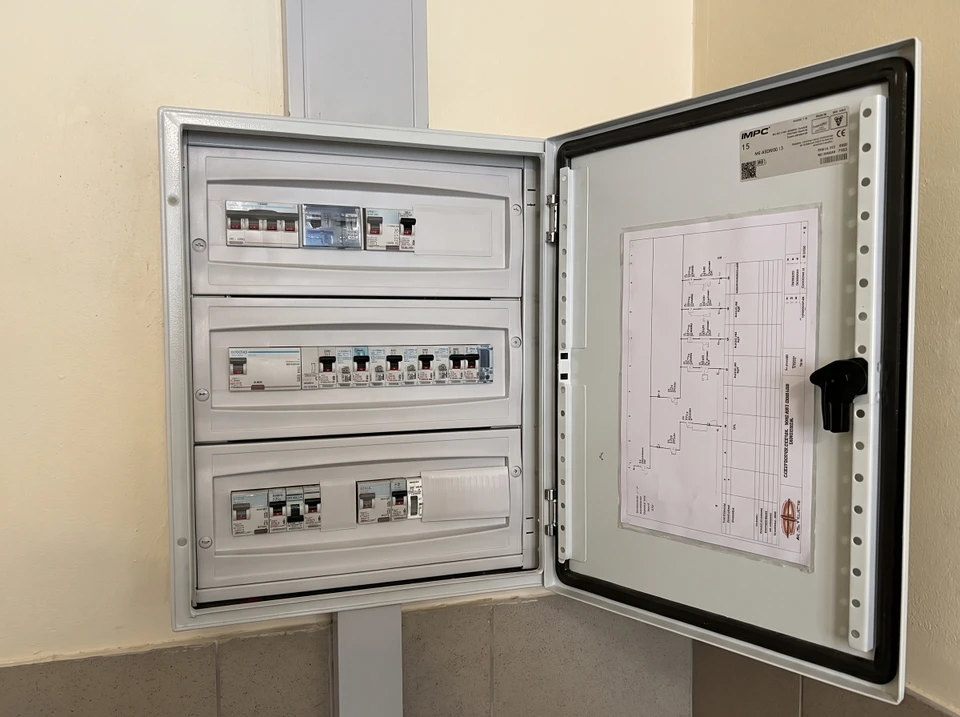 Armoire électrique industrielle IMPC ouverte, fixée au mur, révélant trois rangées de composants : disjoncteurs différentiels, disjoncteurs modulaires et interrupteurs de protection