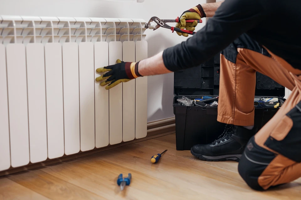 Conseiller en électricité en tenue professionnelle noir et blanc présentant et commentant un plan technique d'installation électrique tertiaire à un client, assis ensemble à une table de bureau en milieu de bureau lumineux, avec schéma de câblage informatique VDI ou plan de réaménagement d'infrastructure visible entre eux.